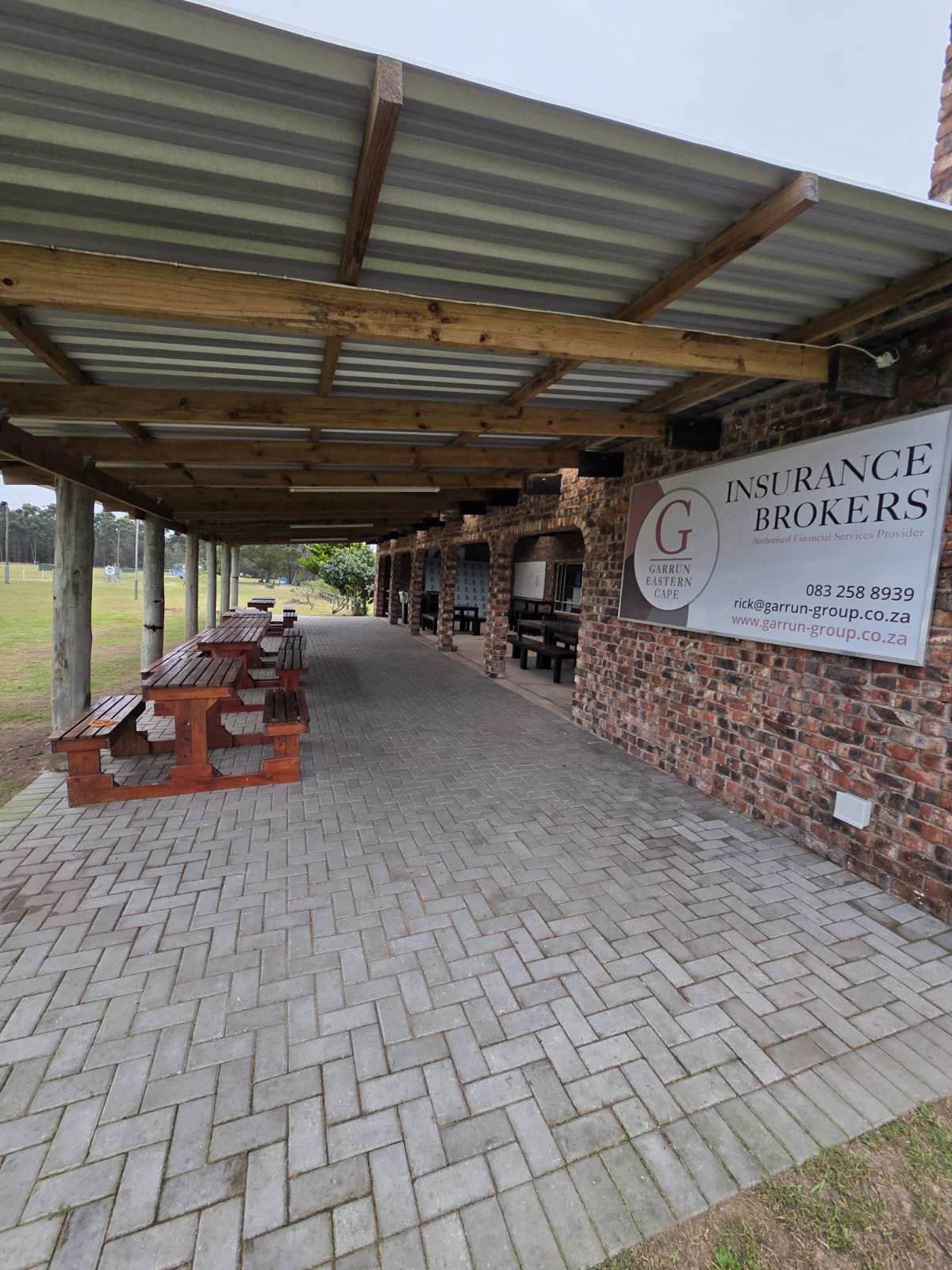 The covered clubhouse veranda at PECTC with wooden picnic tables and the range beyond
