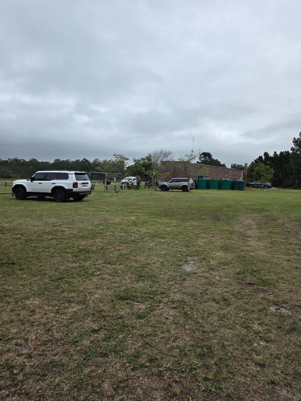 Vehicles parked on the grass at PECTC with the brick clubhouse and green water tanks behind
