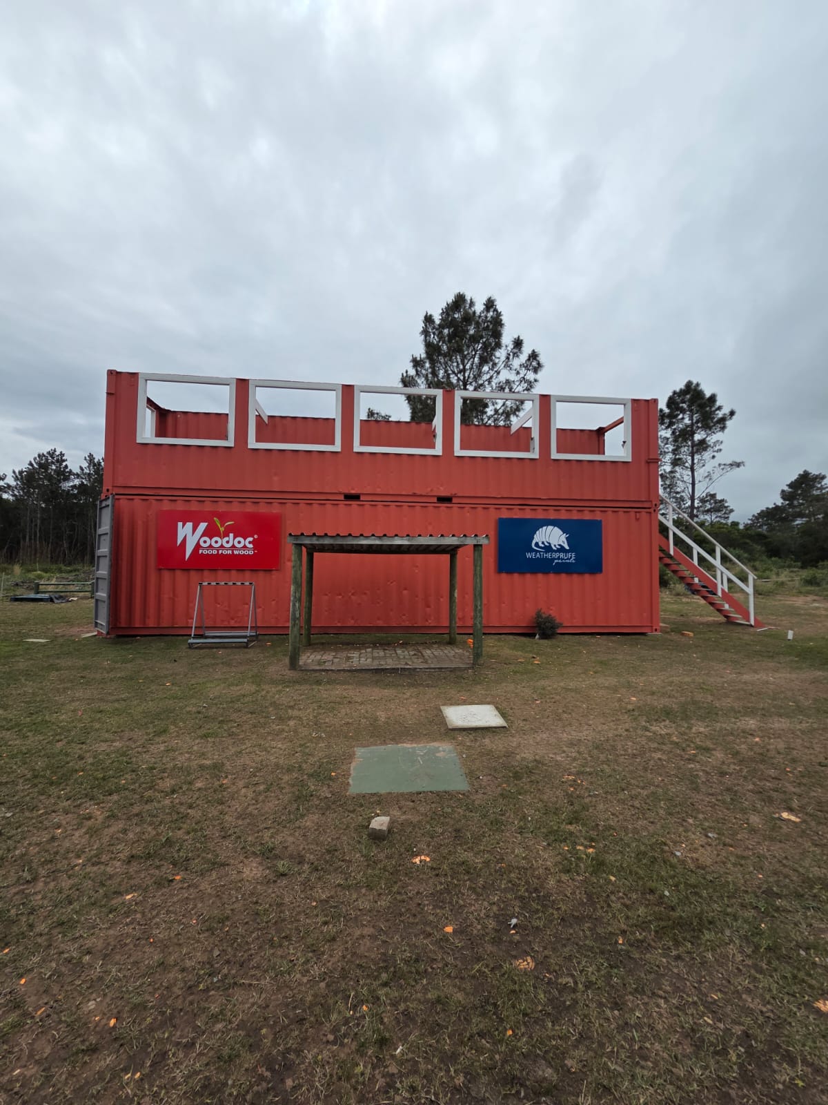 The red container shooting stand at PECTC head-on, with sponsor boards and a covered shooting position beneath