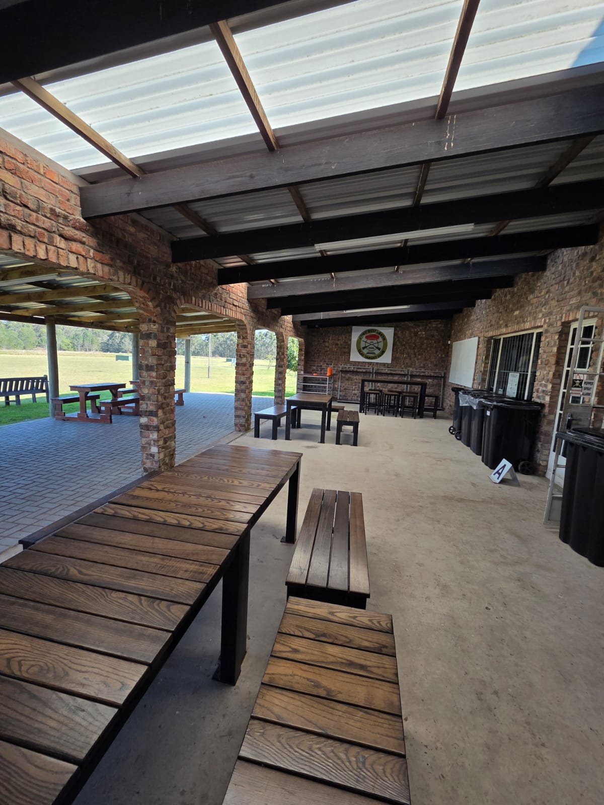 The covered patio at PECTC with long wooden tables and benches under a steel roof