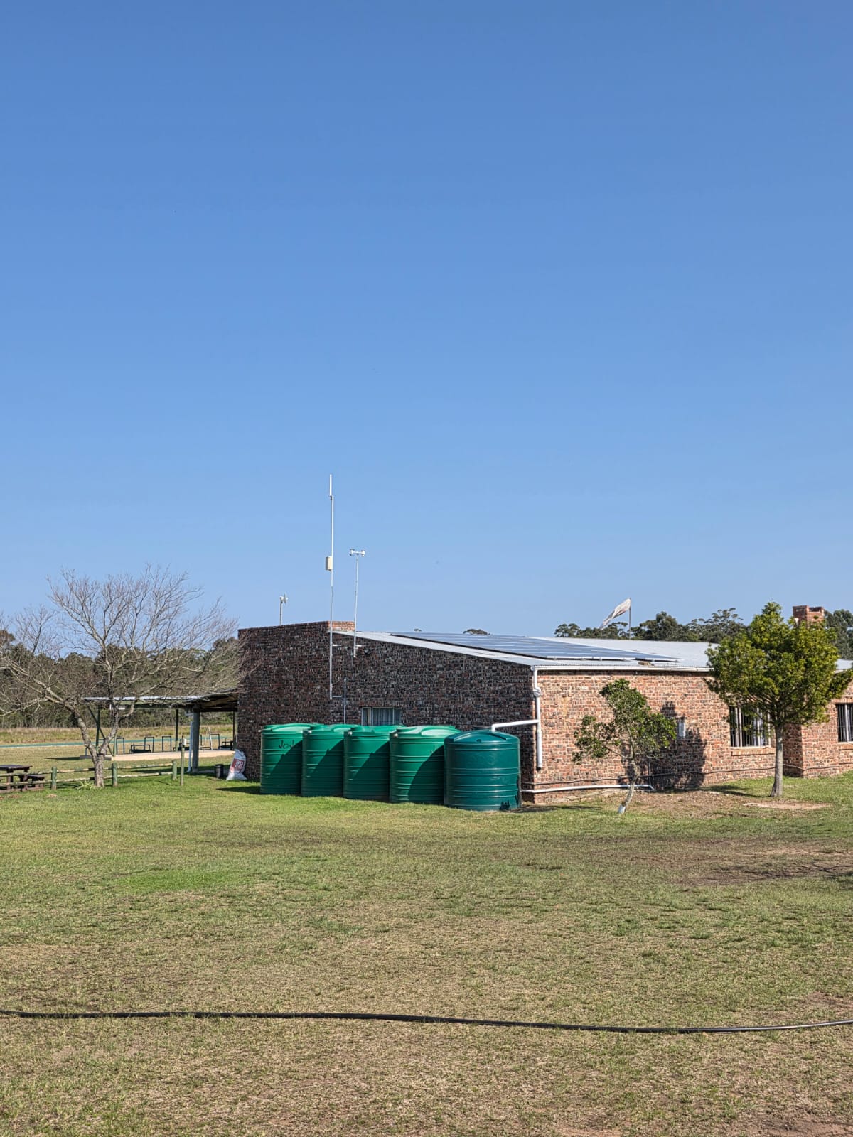 The brick PECTC clubhouse with solar panels and green water tanks alongside