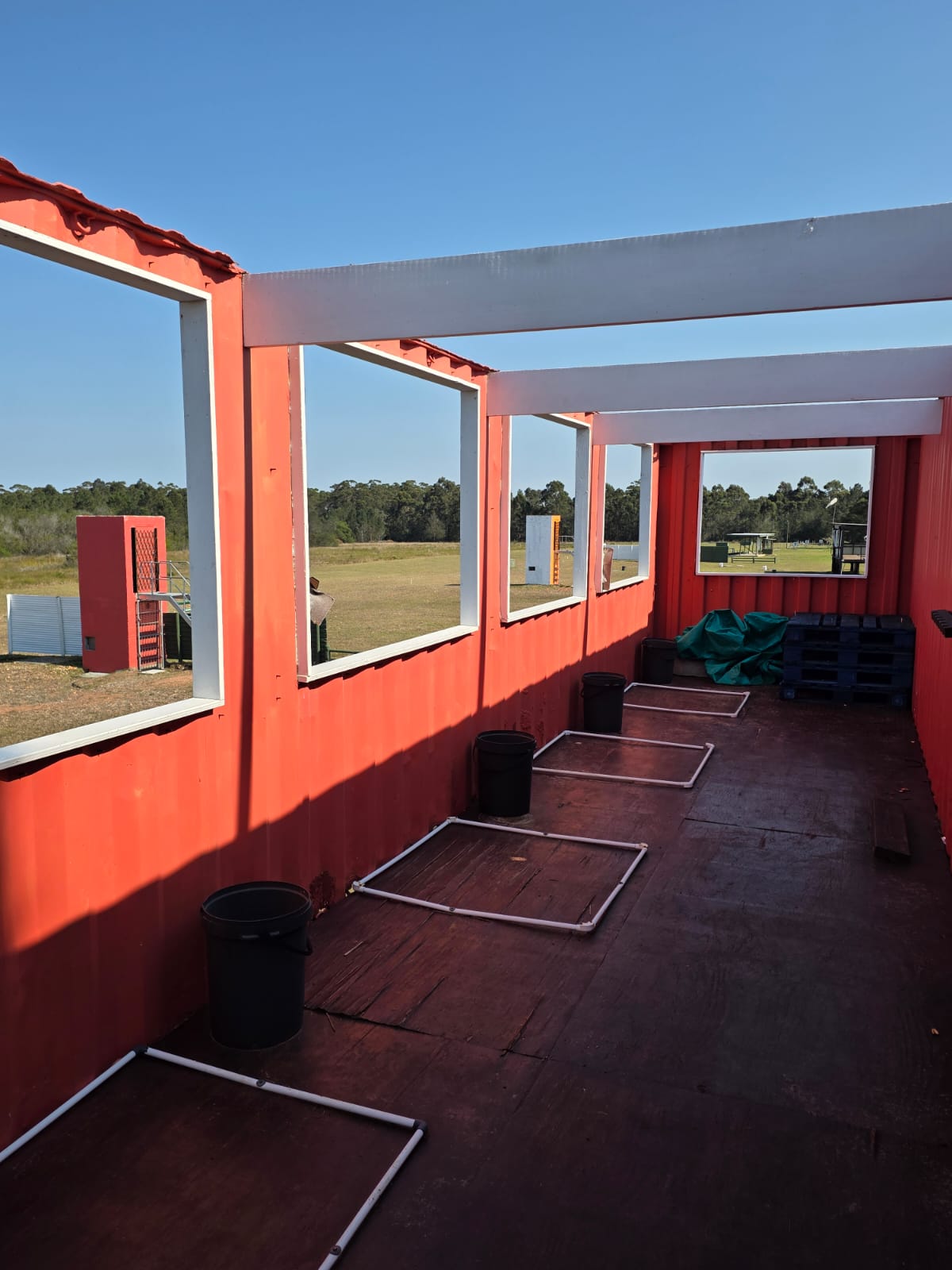 Inside a red covered shooting bay at PECTC with open windows looking out over the range