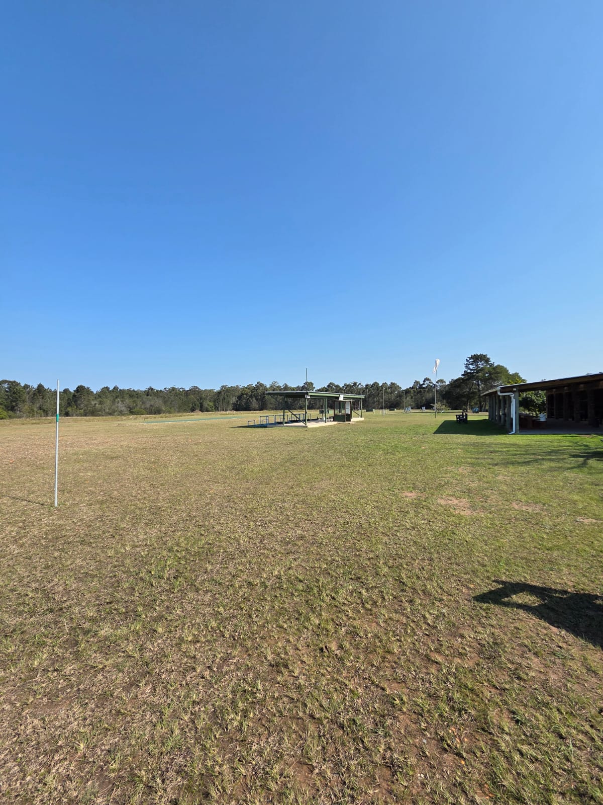 The open grass shooting field at PECTC with the clubhouse veranda on the right
