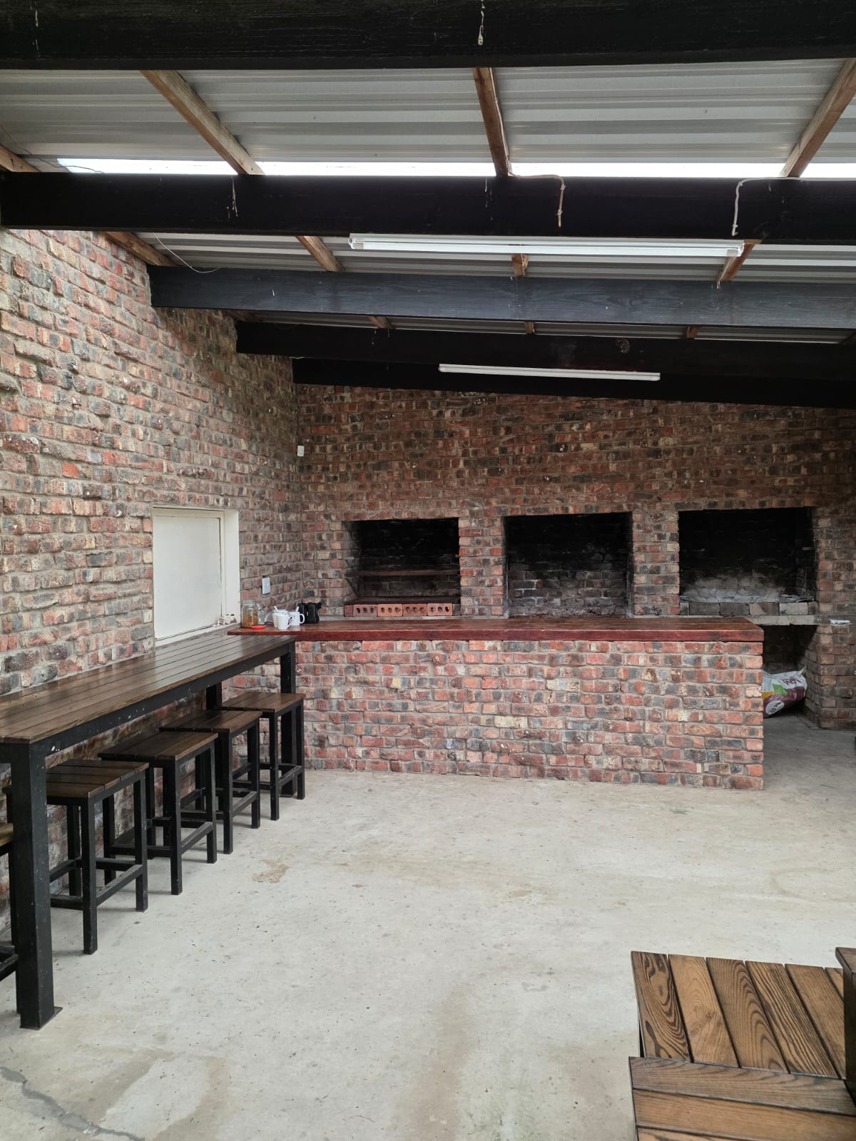 The covered brick braai area at PECTC with built-in fireplaces, benches and tables